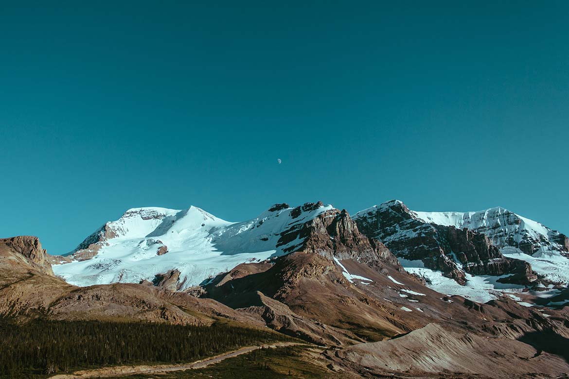 Snow-capped alpine peaks beneath clear teal sky