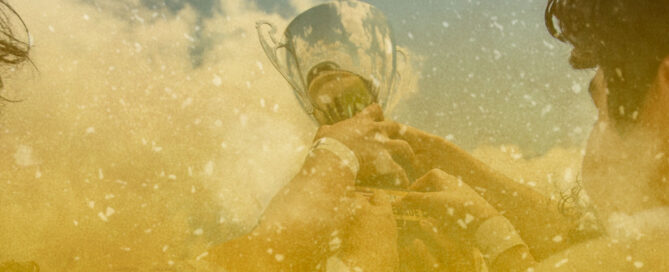 Hands lifting a trophy against blue sky